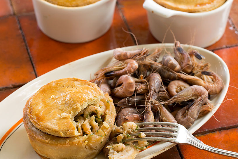 Garnalenpasteitje op een ovaal bord met losse garnalen ernaast